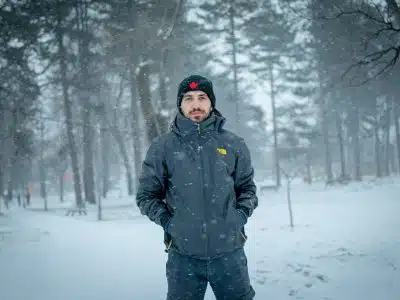 man in black jacket standing on snow covered ground