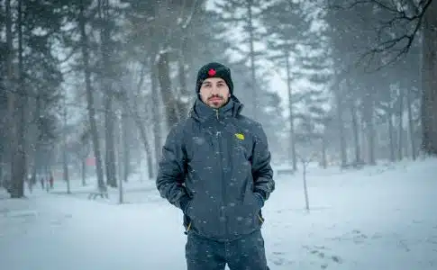 man in black jacket standing on snow covered ground